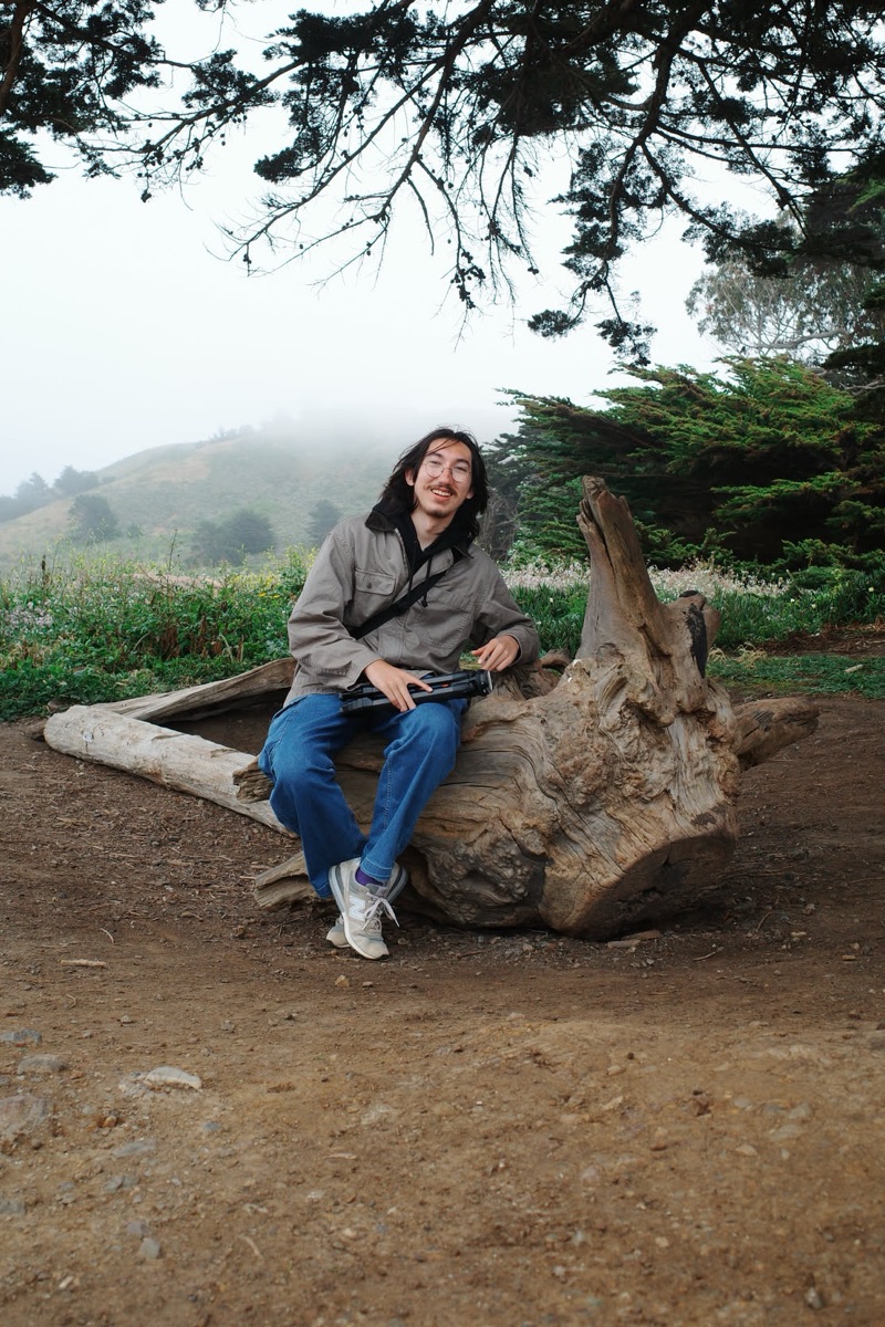 alex sitting on a tree stump in the fog